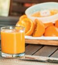 Friskpresset juice med appelsiner i baggrunden